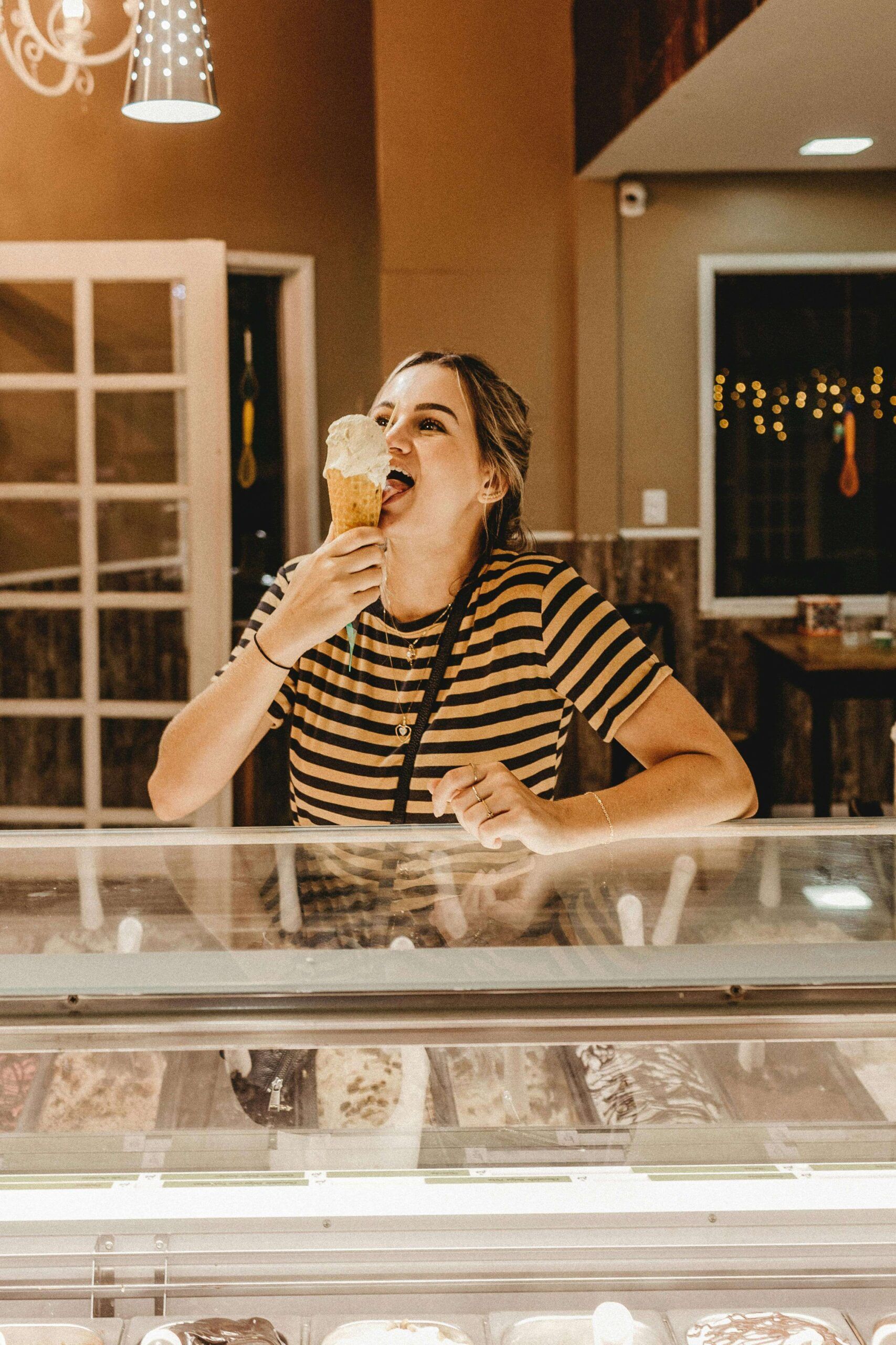 A woman enjoys an ice cream cone at a dessert shop, embracing a balanced approach to eating. Explore nutritional counseling in Raleigh, NC, and support from a dietitian in Hendersonville, NC for a stress-free relationship with food.