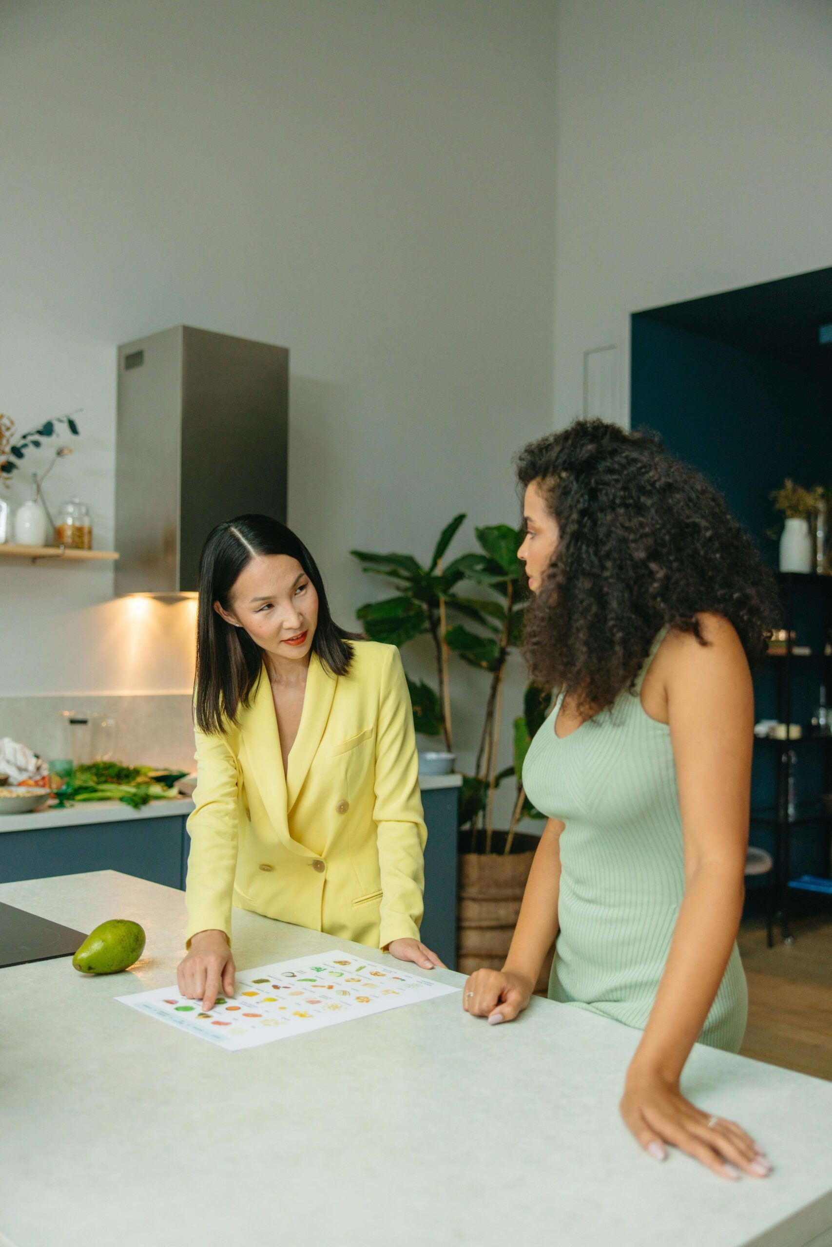 A nutritional therapist in Raleigh, NC meets with a client at a kitchen counter, reviewing a colorful food guide together during a nutrition counseling session in Raleigh, NC.