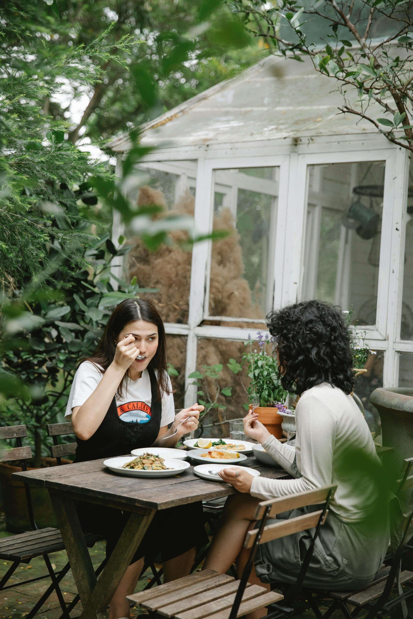 Two women share a peaceful meal together in a garden setting, reflecting the supportive, judgment-free approach of a registered dietitian in Raleigh, NC and the compassionate care of a nutritional therapist in Raleigh, NC.