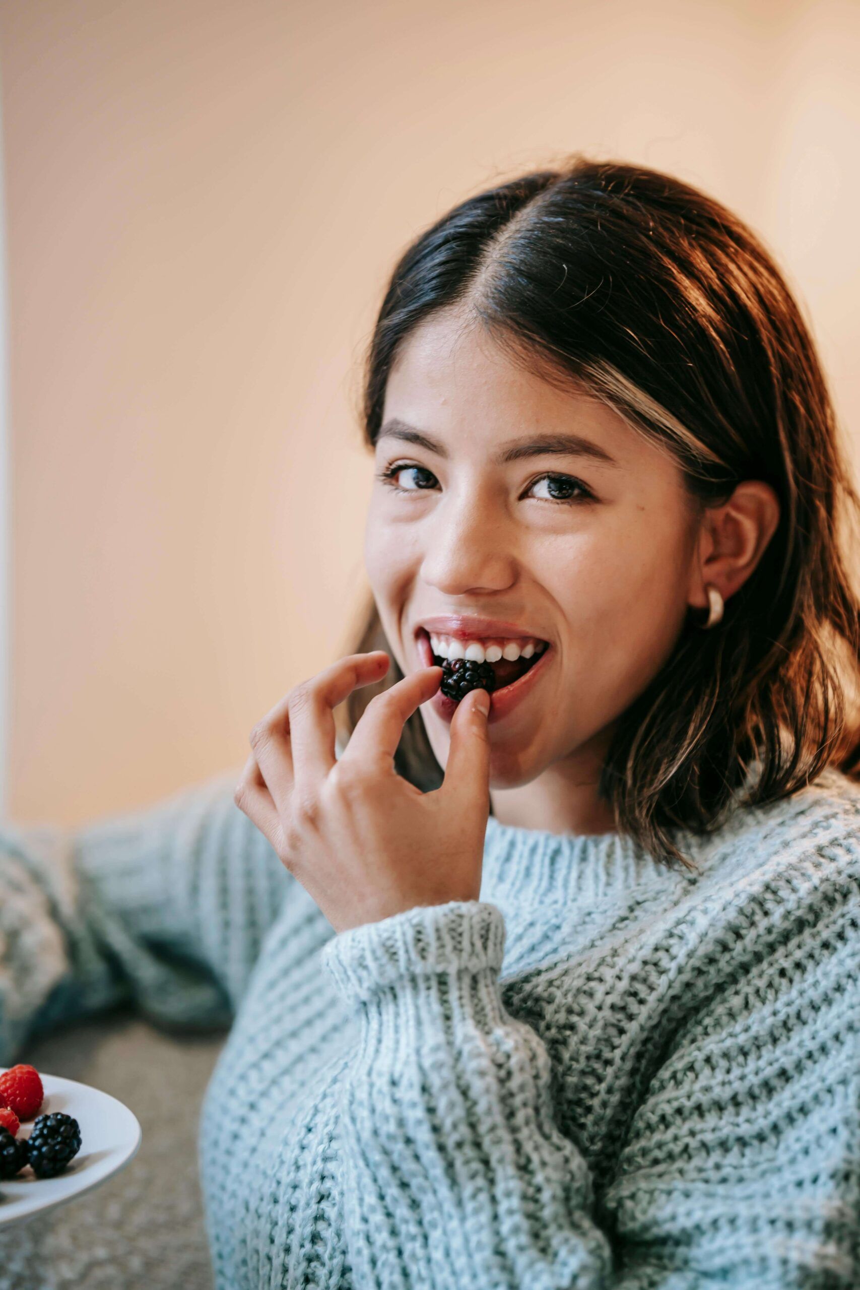 A woman enjoys a fresh blackberry with ease, reflecting the peace and confidence supported by nutritional counseling in Raleigh, NC with a registered dietitian in Raleigh, NC.