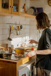 A woman prepares food in a cozy kitchen, reflecting the everyday moments supported through nutrition therapy in Raleigh, NC and compassionate nutrition counseling for eating disorders in Raleigh, NC.
