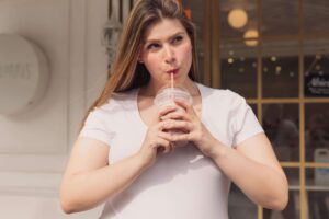 A woman enjoys a smoothie outdoors, capturing a moment of self-care and body connection supported by a registered dietitian in Raleigh, NC through nutritional counseling in Raleigh, NC.
