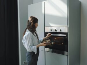 A woman places a homemade dish into the oven, reflecting the everyday nourishment and self-care explored with a nutritional therapist in Raleigh, NC through compassionate nutrition therapy in Raleigh, NC.