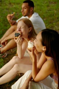 Three friends enjoy cupcakes and pastries outdoors, illustrating joyful eating and the compassionate, nonjudgmental support offered through nutritional counseling in Raleigh, NC and nutrition counseling in Raleigh, NC.