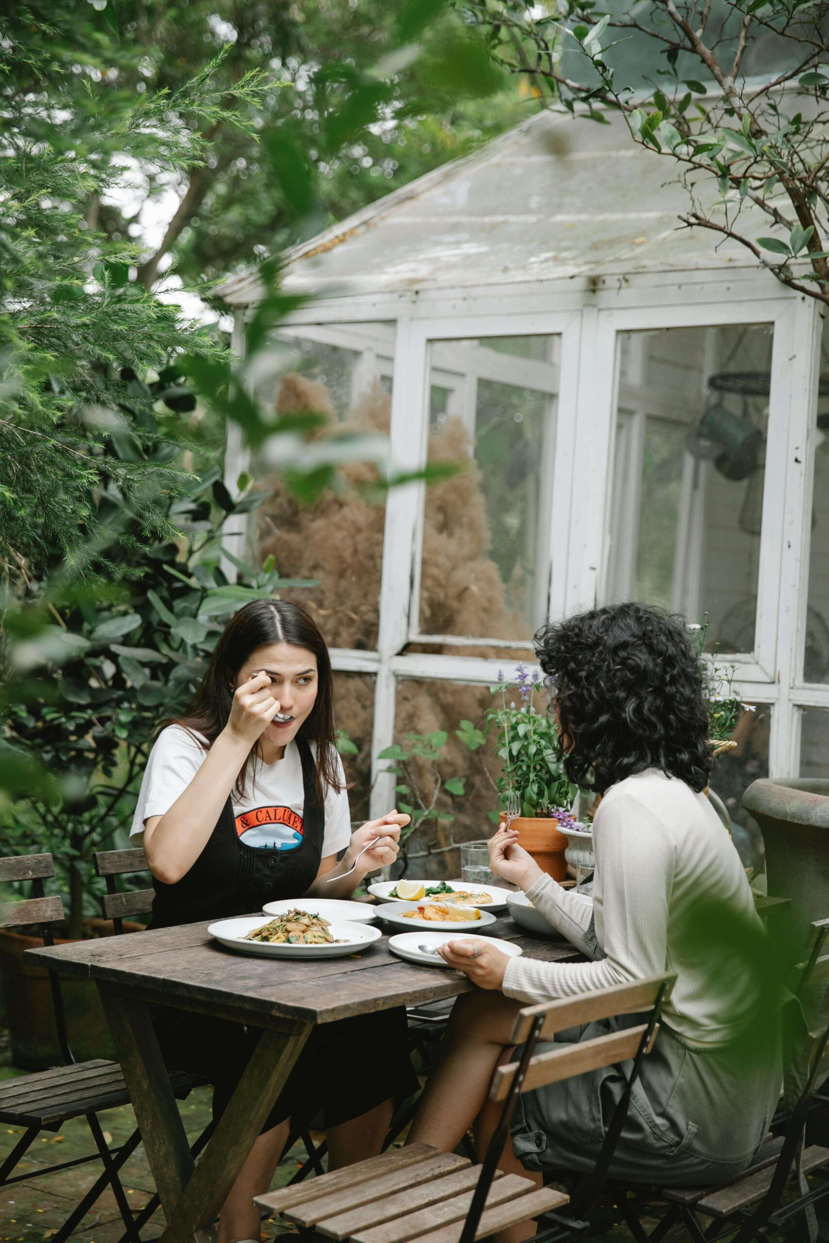 Two women share a peaceful meal together in a garden setting, reflecting the supportive, judgment-free approach of a registered dietitian in Raleigh, NC and the compassionate care of a nutritional therapist in Raleigh, NC.