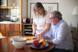 An older couple prepares fresh fruit together at home, representing how a nutritional therapist in Raleigh, NC or a registered dietitian in Raleigh, NC can support joyful, accessible eating habits at every age.
