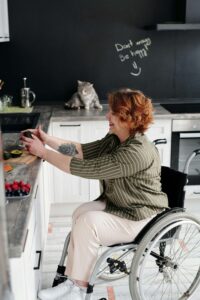 A woman in a wheelchair smiles while preparing fresh fruit and avocados in her kitchen, representing the supportive, inclusive approach of nutritious counseling for eating disorders in Asheville, NC and nutrition counseling in Raleigh, NC.