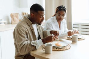 Two Black adults enjoy a calm meal together at home, illustrating how support from a registered dietitian in Raleigh, NC and nutrition counseling in Raleigh, NC can foster more peaceful, connected food experiences.