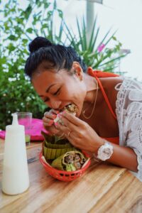 A woman enjoys a flavorful wrap outdoors, embodying the joyful, flexible approach promoted by a registered dietitian in Raleigh, NC and nutritional therapist in Raleigh, NC who honors cultural foods and satisfaction in nutritional care.