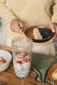 Person enjoying a simple breakfast of fruit and a smoothie, demonstrating low-barrier nutrition strategies. A nutritional therapist in Raleigh, NC, offering medical nutrition therapy in Raleigh, NC, helps neurodivergent adults create sustainable, low-effort meal options.
