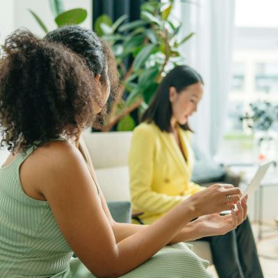 A client in a green dress engages in a discussion during a nutritional counseling session in Raleigh, NC, while a nutritionist in Asheville, NC takes notes on a laptop in a bright, welcoming office.